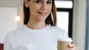 Cheerful female with takeaway coffee in office