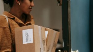 Ethnic woman entering house with cardboard boxes