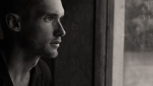 Grayscale Photography of Man Facing Glass Panel