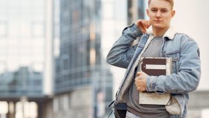 Man in Blue Denim Jacket Holding Books