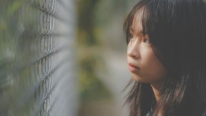 Thoughtful Asian girl looking through grid