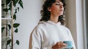 Young sad woman with mug of hot drink...