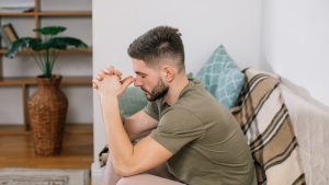 A Man Sitting on a Sofa while His Hands are Together