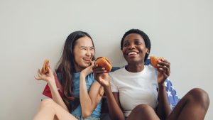 Woman in Blue Shirt Beside a Woman in White Shirt Holding a Plate with Food